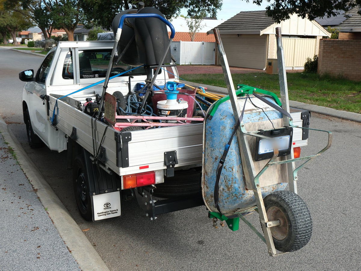 Ute tray loaded with tools and materials while the wheelbarrow rides upright on the tow hitch with Barry